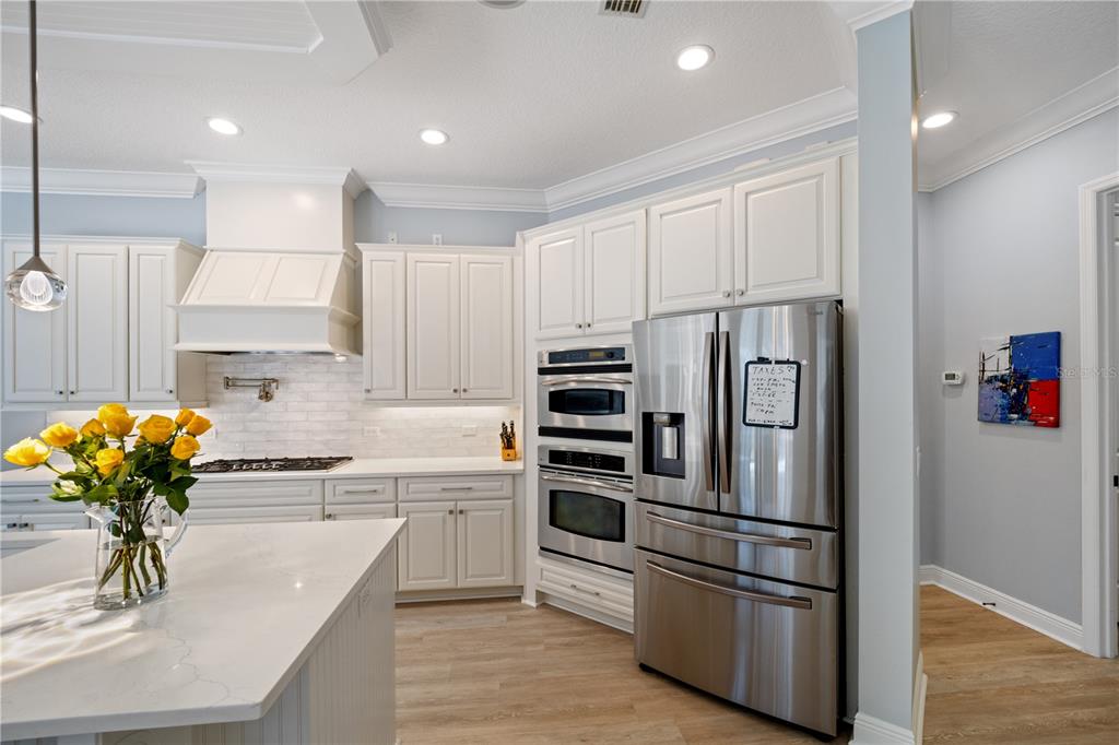 14721 Bowfin Terrace Lakewood Ranch, FL 34202 - Photo 5 of 50 a kitchen with stainless steel appliances a refrigerator sink cabinets and wooden floor