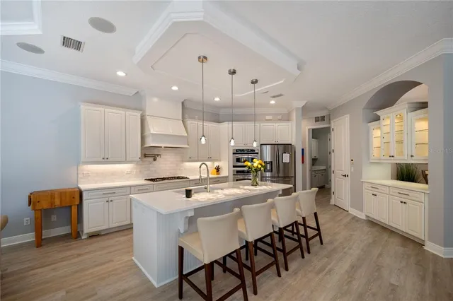 a kitchen with stainless steel appliances kitchen island granite countertop a table chairs sink and cabinets
