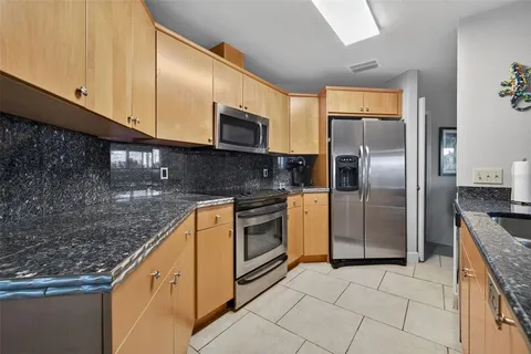 a kitchen with stainless steel appliances granite countertop a refrigerator a stove and a sink