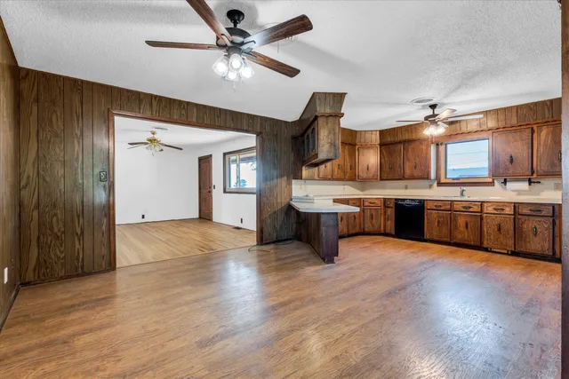 a large kitchen with stainless steel appliances a stove a sink dishwasher a refrigerator and a fireplace with wooden floor