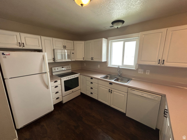 432 Spring Lane Logan, UT 84341 - Photo 12 of 22 Kitchen with white cabinets, light countertops, white appliances, and a textured ceiling