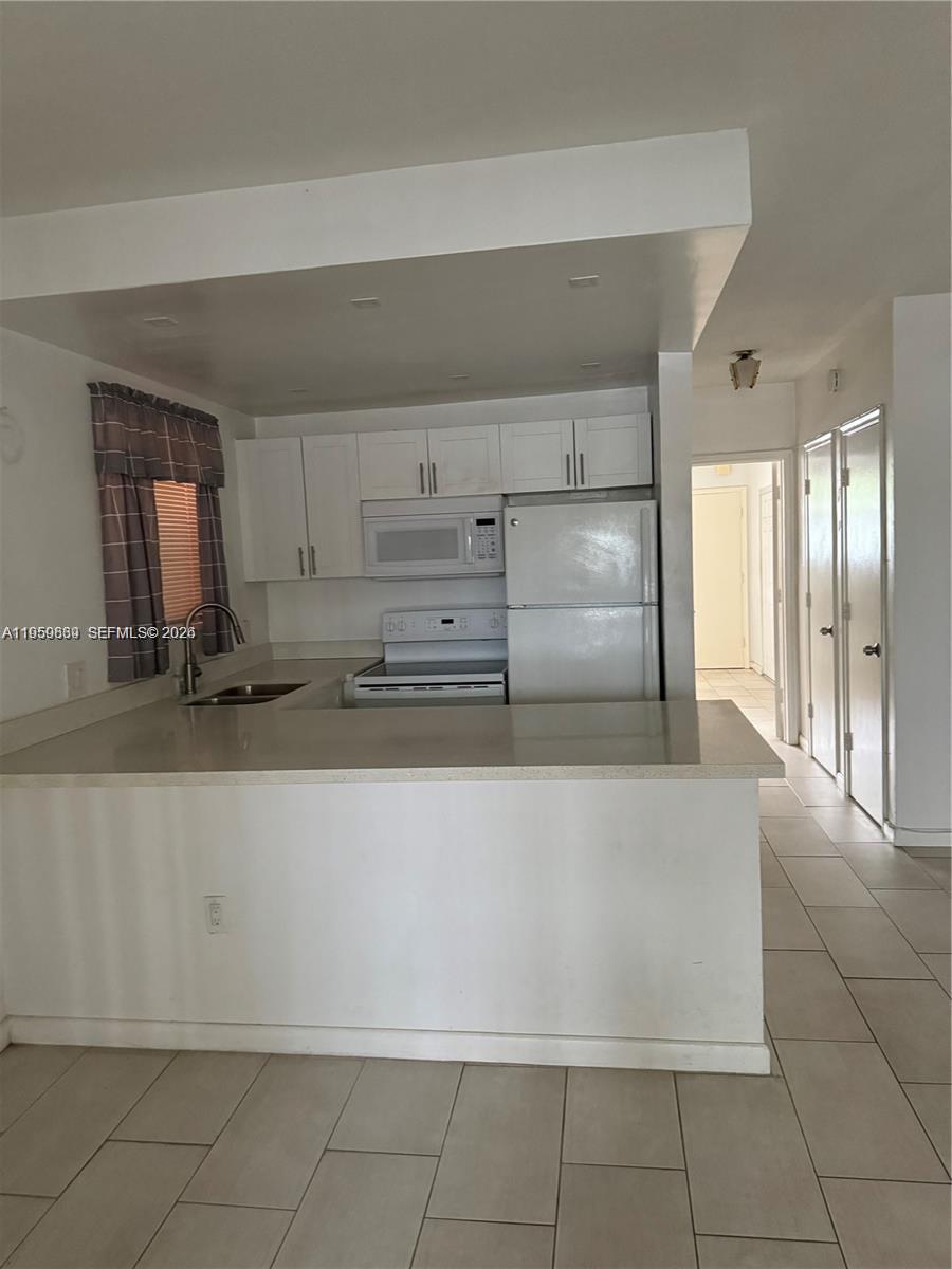 285 Northeast 191st Street, Unit 2907 Miami, FL 33179 - Photo 2 of 13 a large kitchen with granite countertop a sink a stove and a refrigerator