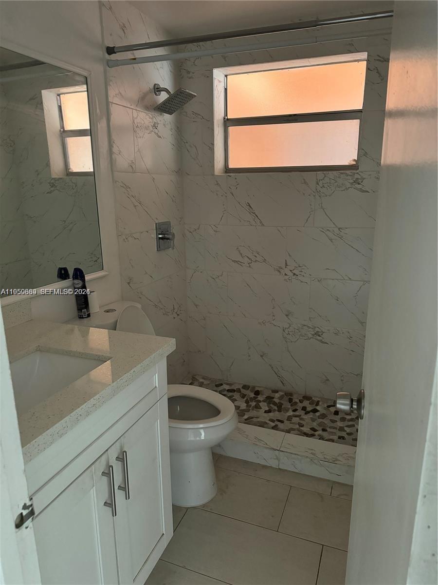 285 Northeast 191st Street, Unit 2907 Miami, FL 33179 - Photo 9 of 13 a bathroom with a granite countertop sink a toilet and a mirror