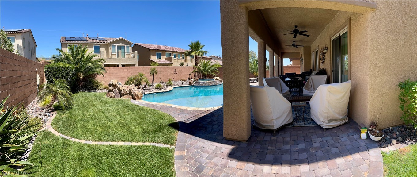 9724 University Ridge Avenue Las Vegas, NV 89149 - Photo 26 of 61 A spacious backyard oasis features a freeform pool, lush lawn, and a shaded patio area perfect for entertaining.