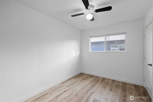 an empty room with a window and a ceiling fan
