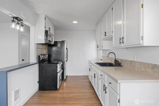 a kitchen with stainless steel appliances a sink stove refrigerator and cabinets