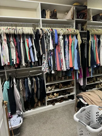 a view of walk in closet with clothes and shoes