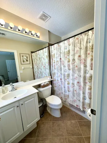 a bathroom with a granite countertop sink toilet and mirror