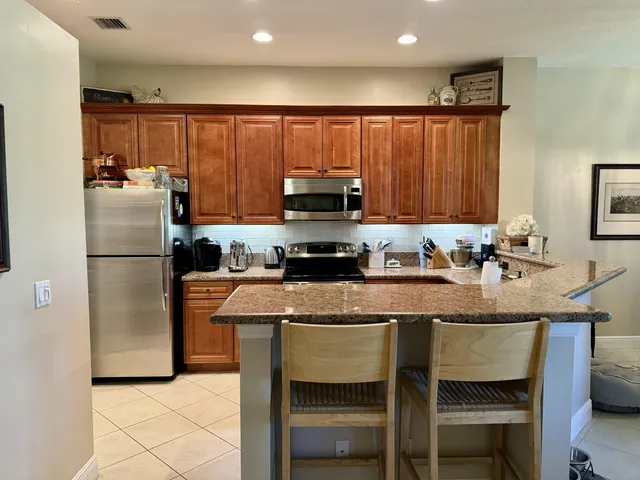 a kitchen with granite countertop a refrigerator a stove a sink and a microwave