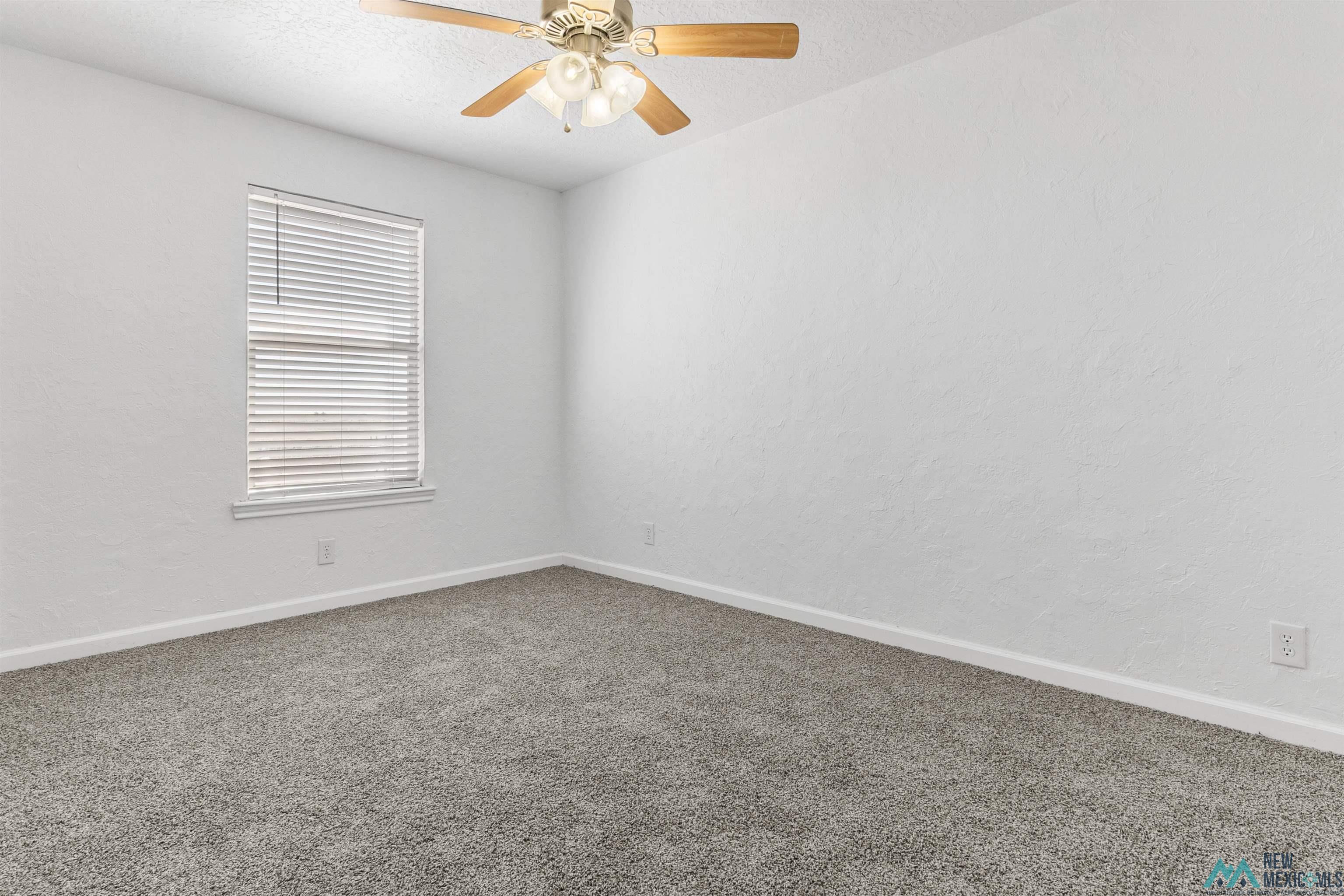 1691 County Rd K Clovis, NM 88101 - Photo 14 of 22 Spare room with dark colored carpet, ceiling fan, and a textured wall