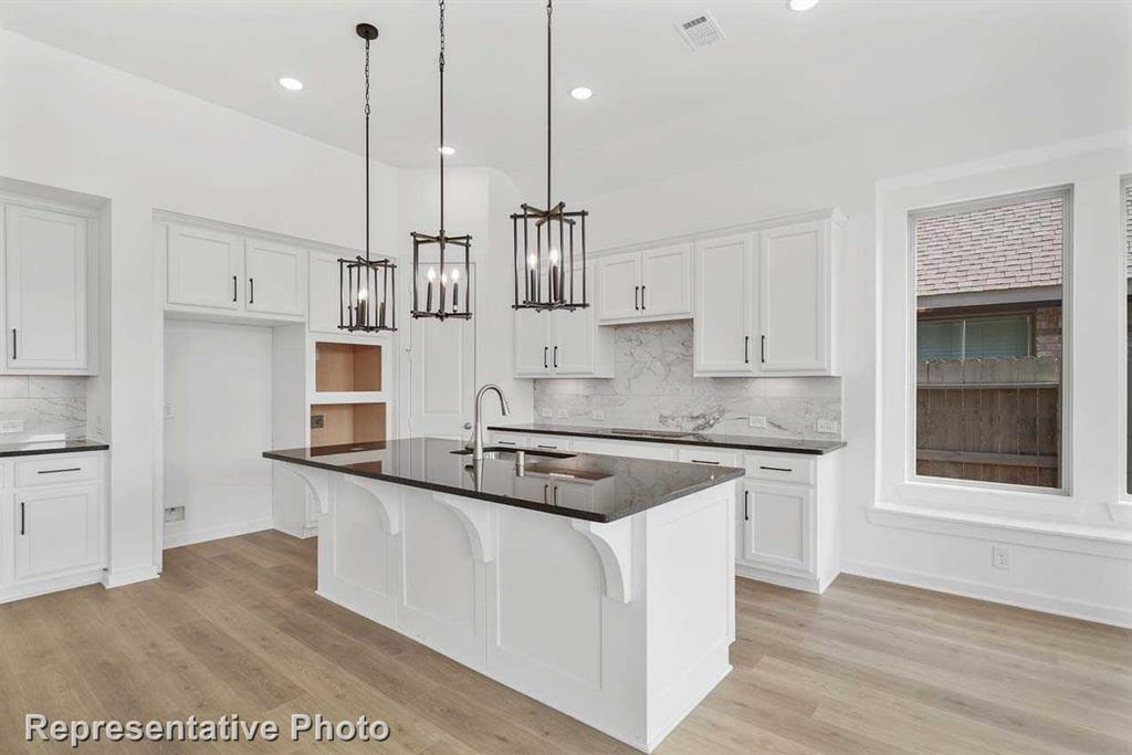 a kitchen with stainless steel appliances granite countertop a sink a stove and a wooden floor