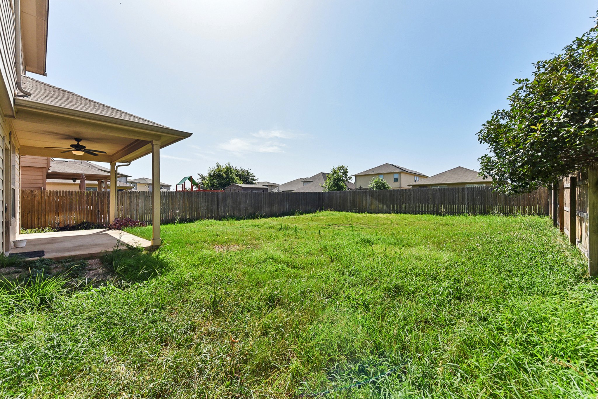 310 Potters Peak Way Georgetown, TX 78626 - Photo 5 of 21 Expansive backyard featuring a covered patio with ceiling fan, a lush green lawn, and a perimeter wood fence