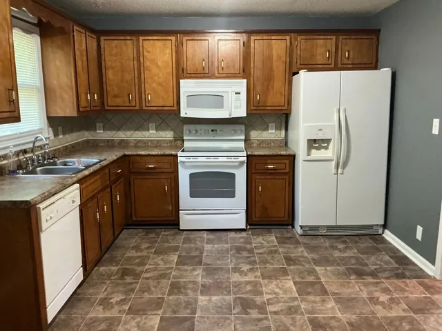 a kitchen with stainless steel appliances granite countertop a refrigerator a stove a sink and a microwave