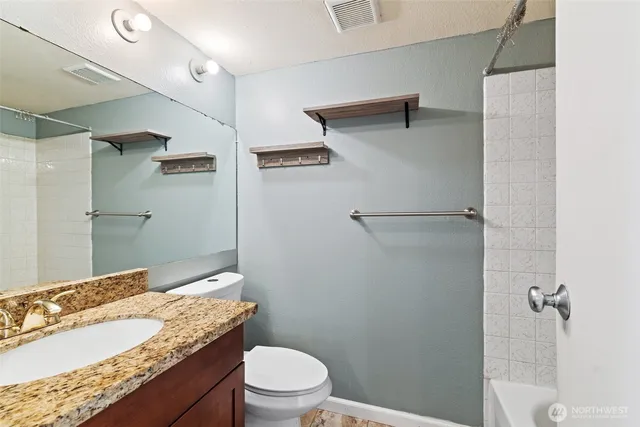 a bathroom with a granite countertop sink toilet and shower