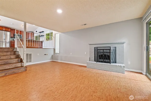 a view of an empty room with a fireplace and a window