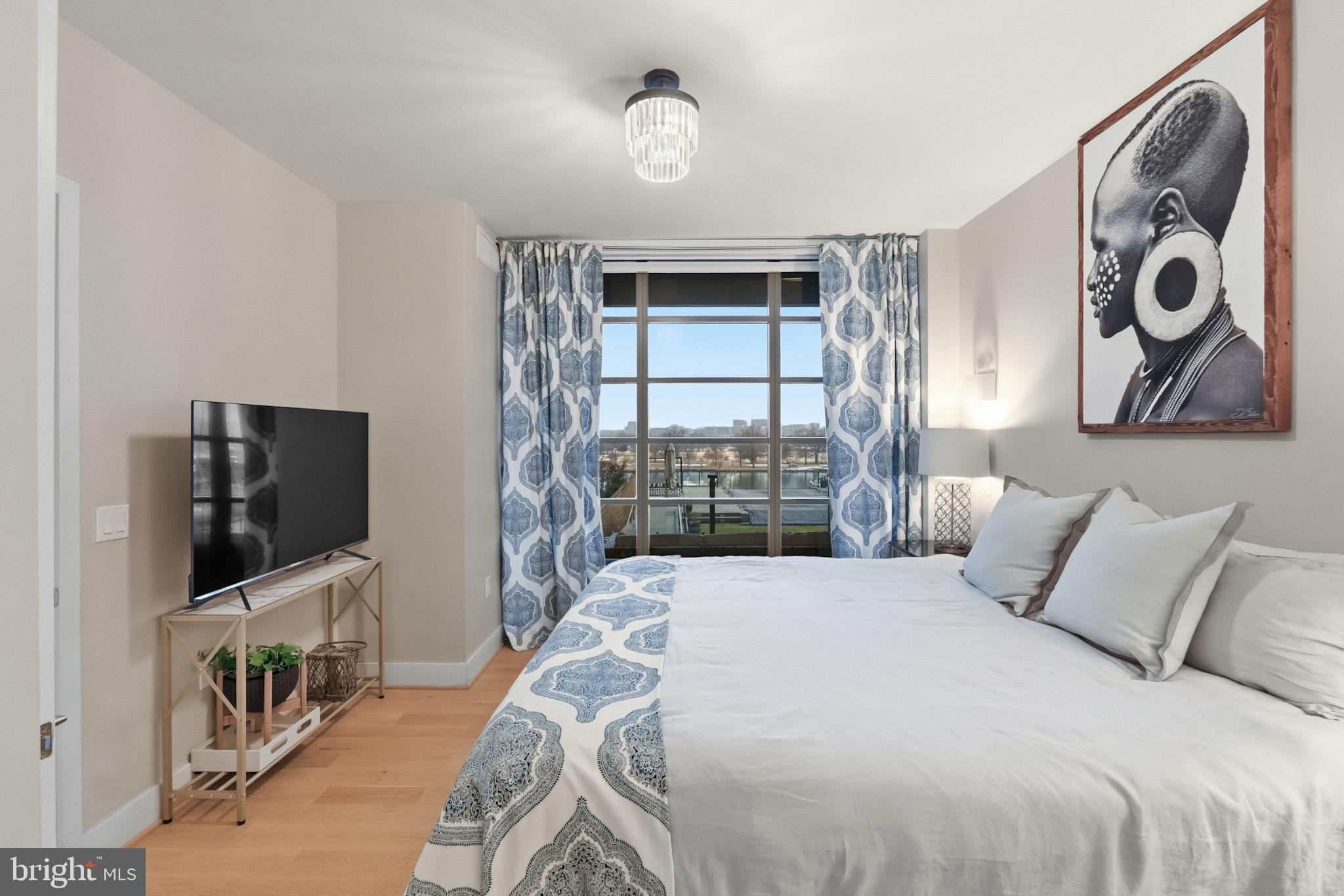 45 Sutton Square Southwest, Unit 403 Washington, DC 20024 - Photo 26 of 80 a bedroom with a bed and a flat tv screen on the dresser