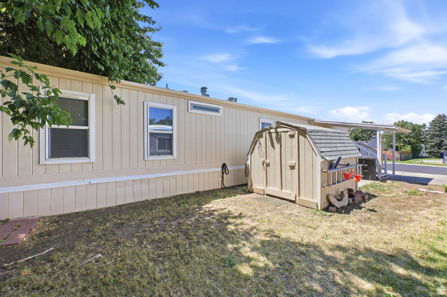 1525 South 400 East, Unit 13 Springville, UT 84663 - Photo 25 of 32 Exterior featuring light-colored vertical siding, multiple windows, a storage shed with a gambrel roof, and a covered porch structure