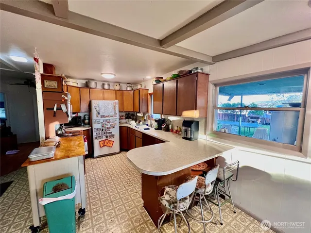 a room with stainless steel appliances kitchen island granite countertop a table chairs and a view of living room