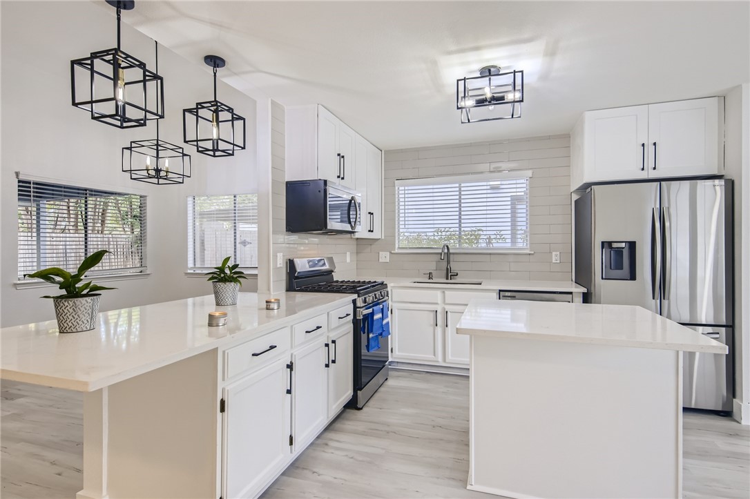 a kitchen with kitchen island granite countertop a sink appliances cabinets and a counter top space