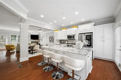 a living room with stainless steel appliances furniture and a wooden floor