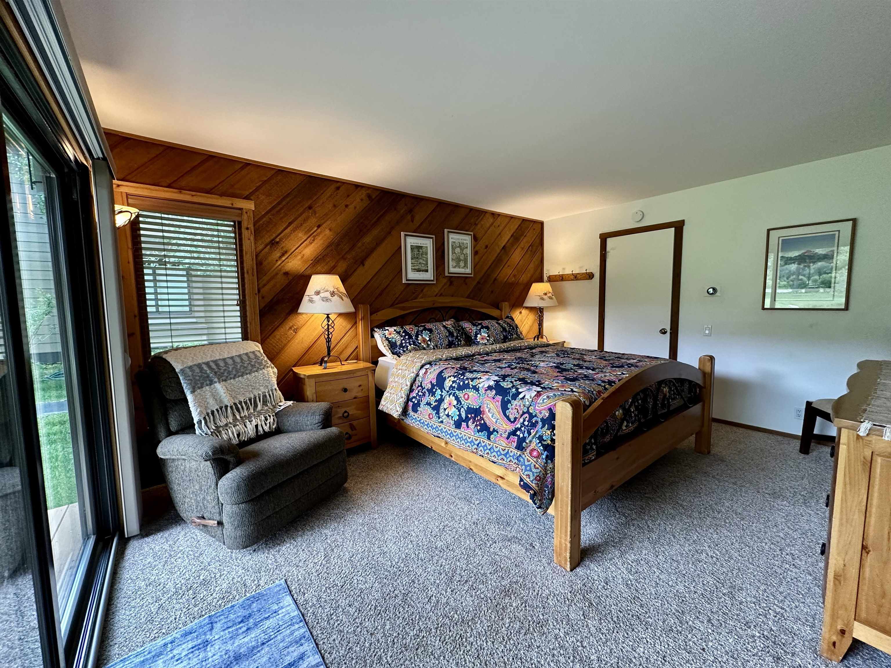 315 Fascination, Unit 315 Mammoth Lakes, CA 93546 - Photo 15 of 44 Carpeted interior space featuring wood-paneled accent wall, sliding glass door, and a built-in wooden headboard