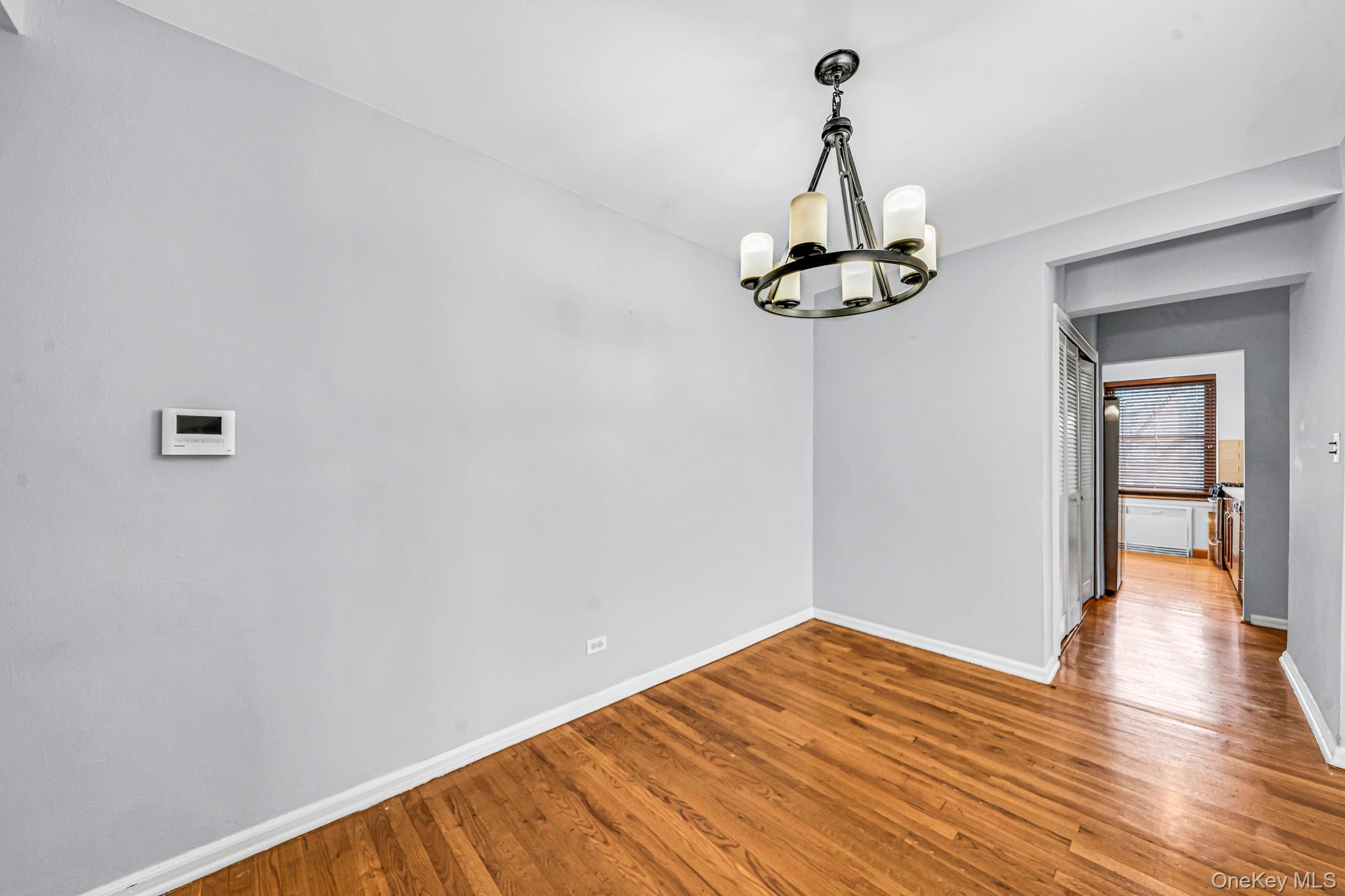 213-05 75th Avenue, Unit 4N Queens, NY 11364 - Photo 6 of 19 Empty room featuring wood finished floors and a chandelier