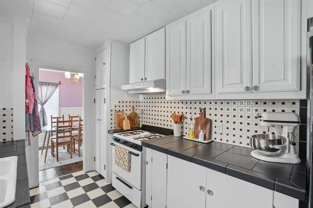 a kitchen with granite countertop a sink a stove and cabinets