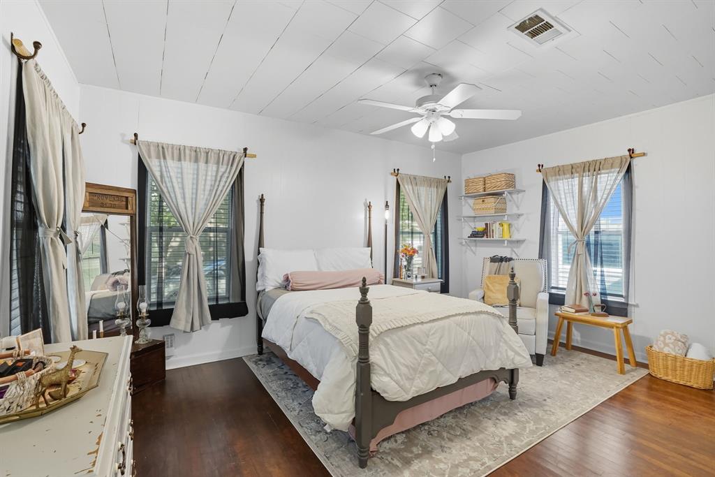 3244 Ryan Avenue Fort Worth, TX 76110 - Photo 20 of 31 a bedroom with a large bed wooden floor and a large window