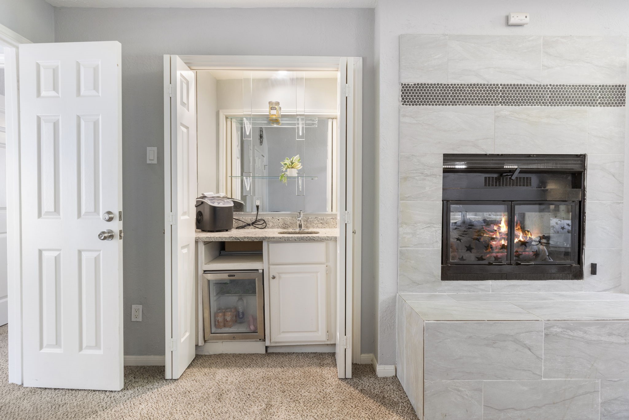 2110 Paso Rello Drive Houston, TX 77077 - Photo 27 of 41 This cozy room features a sleek fireplace with tiled surround, a compact wet bar with granite countertop, and a mini fridge, perfect for primary suite relaxation.