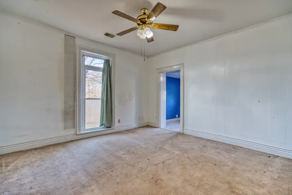 an empty room with closet and a ceiling fan