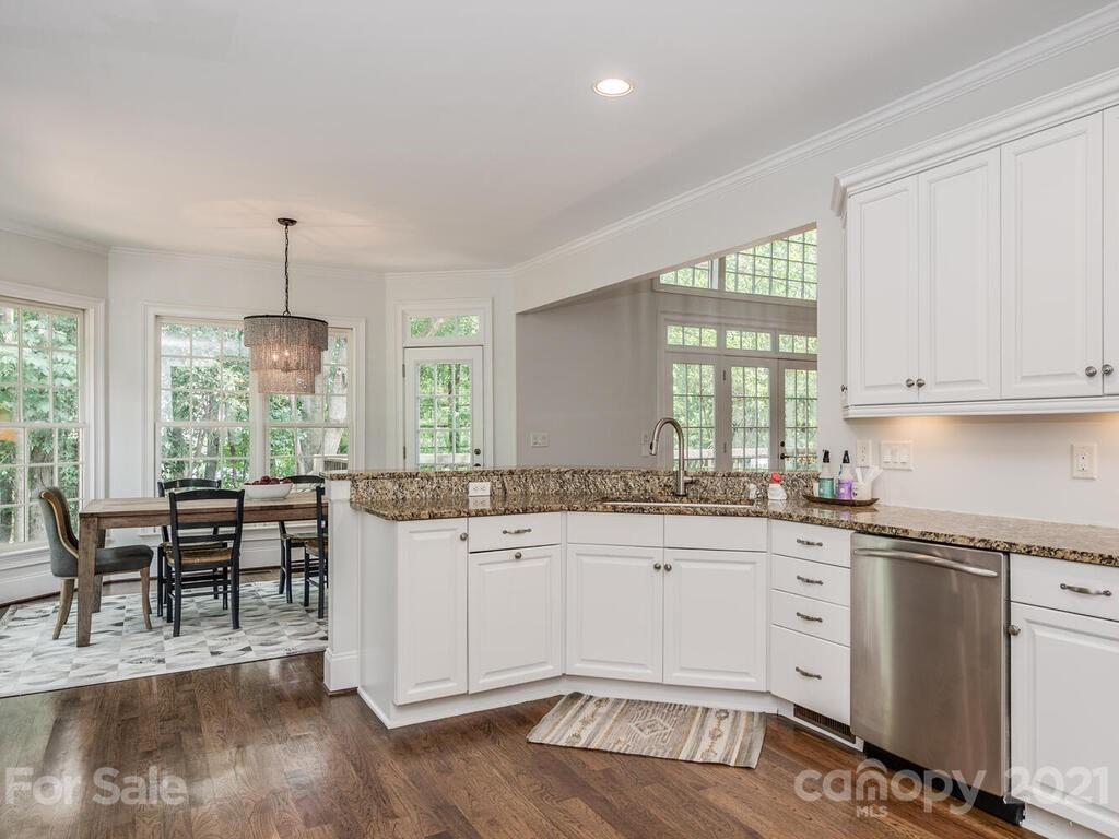 3025 Sharon Road Charlotte, NC 28211 - Photo 8 of 32 a kitchen with granite countertop a stove a sink a dining table and chairs with wooden floor