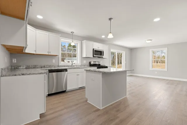 a kitchen with granite countertop white cabinets and black stainless steel appliances