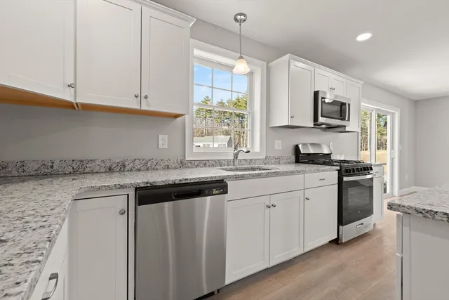 a kitchen with stainless steel appliances granite countertop a stove a sink and a microwave