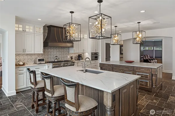 a kitchen with stainless steel appliances granite countertop a stove a refrigerator a kitchen island a sink and chairs