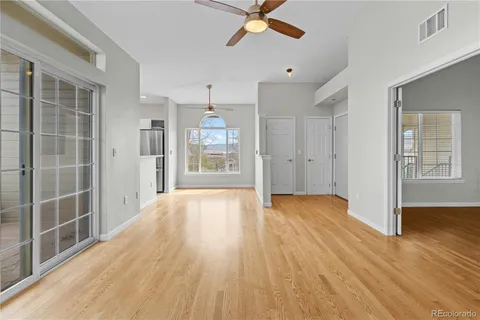 a view of empty room with wooden floor and fan