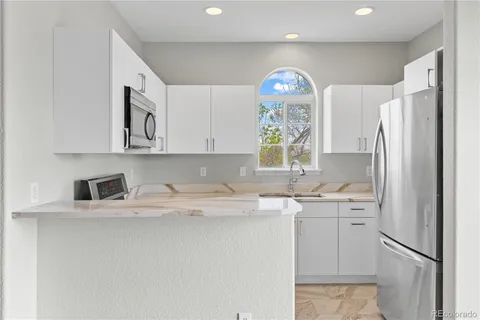 a kitchen with stainless steel appliances a sink a stove a refrigerator a window