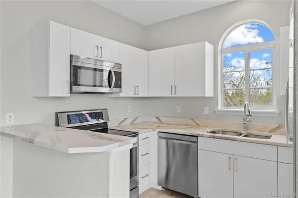a kitchen with stainless steel appliances granite countertop a sink a stove and cabinets
