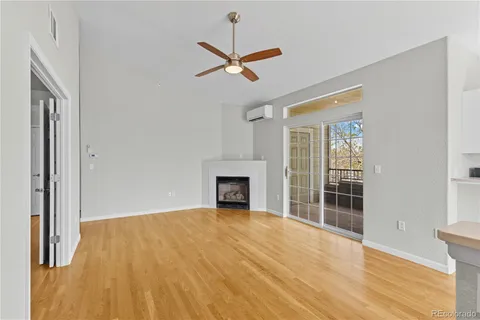 a view of a livingroom with a fireplace a ceiling fan and front door