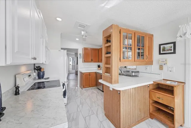 a large white kitchen with kitchen island a stove a sink dishwasher and a dining table with wooden cabinet