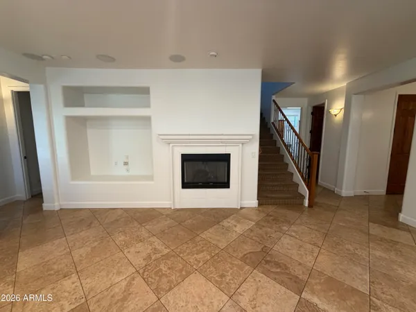 a view of an empty room with wooden floor and a fireplace