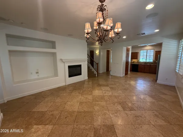 a view of a livingroom with a chandelier fan and kitchen view