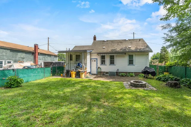 a backyard of a house with table and chairs plants and large tree