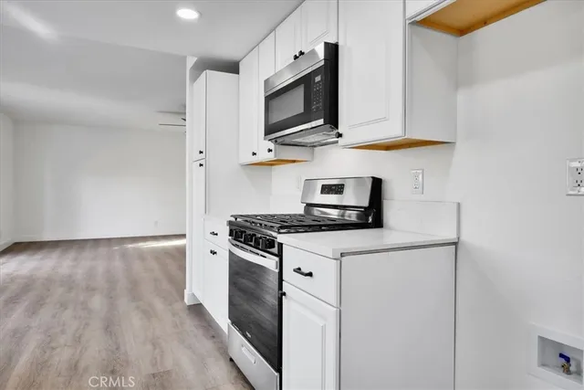 a kitchen with stainless steel appliances a stove a microwave and white cabinets