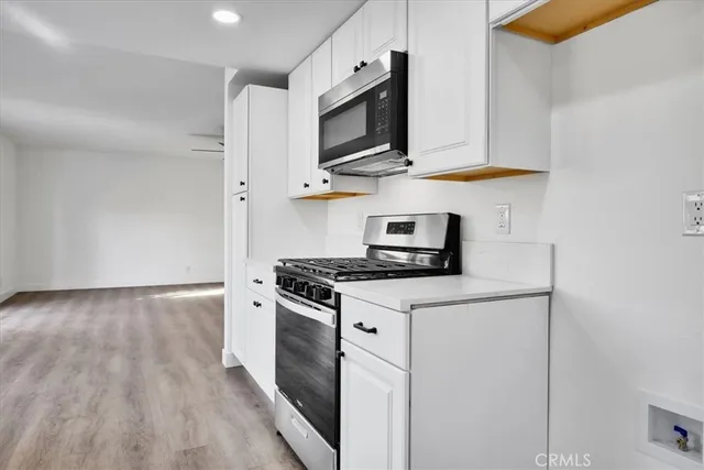 a kitchen with stainless steel appliances a stove a microwave and white cabinets