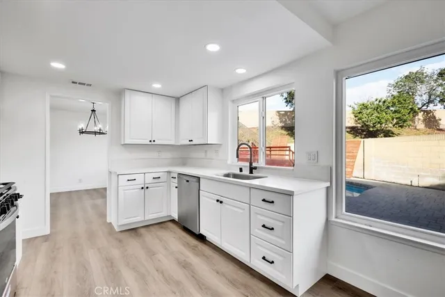 a kitchen with white cabinets and wooden floors