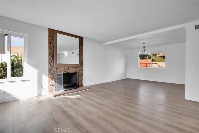 an empty room with windows and fireplace