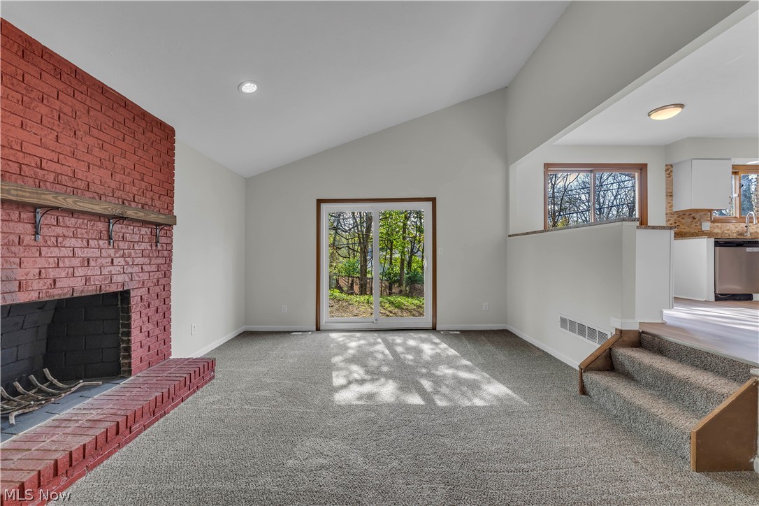 2540 Charney Road University Heights, OH 44118 - Photo 9 of 44 Carpeted living area featuring a brick fireplace with wood mantel, vaulted ceiling, recessed lighting, and sliding glass door to exterior