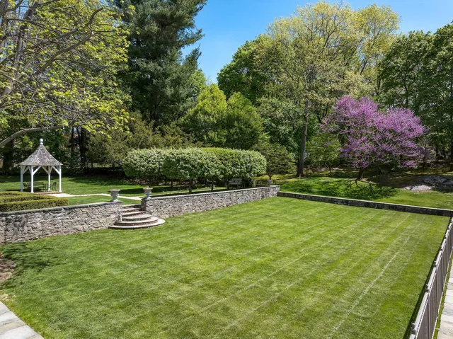a view of house with a big yard and large trees