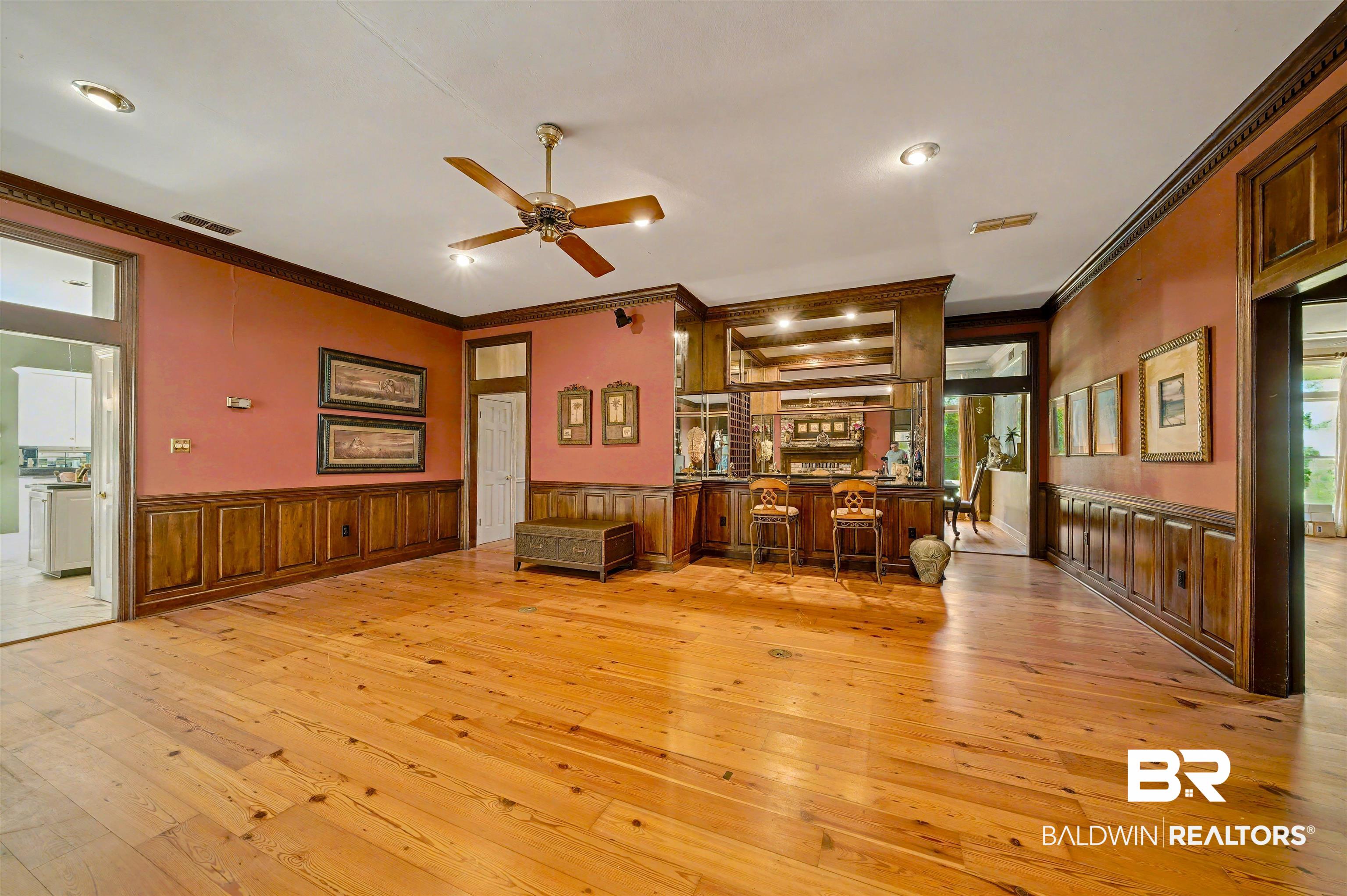 15810 County Road 73 Foley, AL 36535 - Photo 15 of 56 Unfurnished room with light wood finished floors, ornamental molding, wainscoting, bar, and ceiling fan