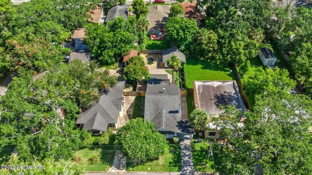 an aerial view of a house with outdoor space and trees all around